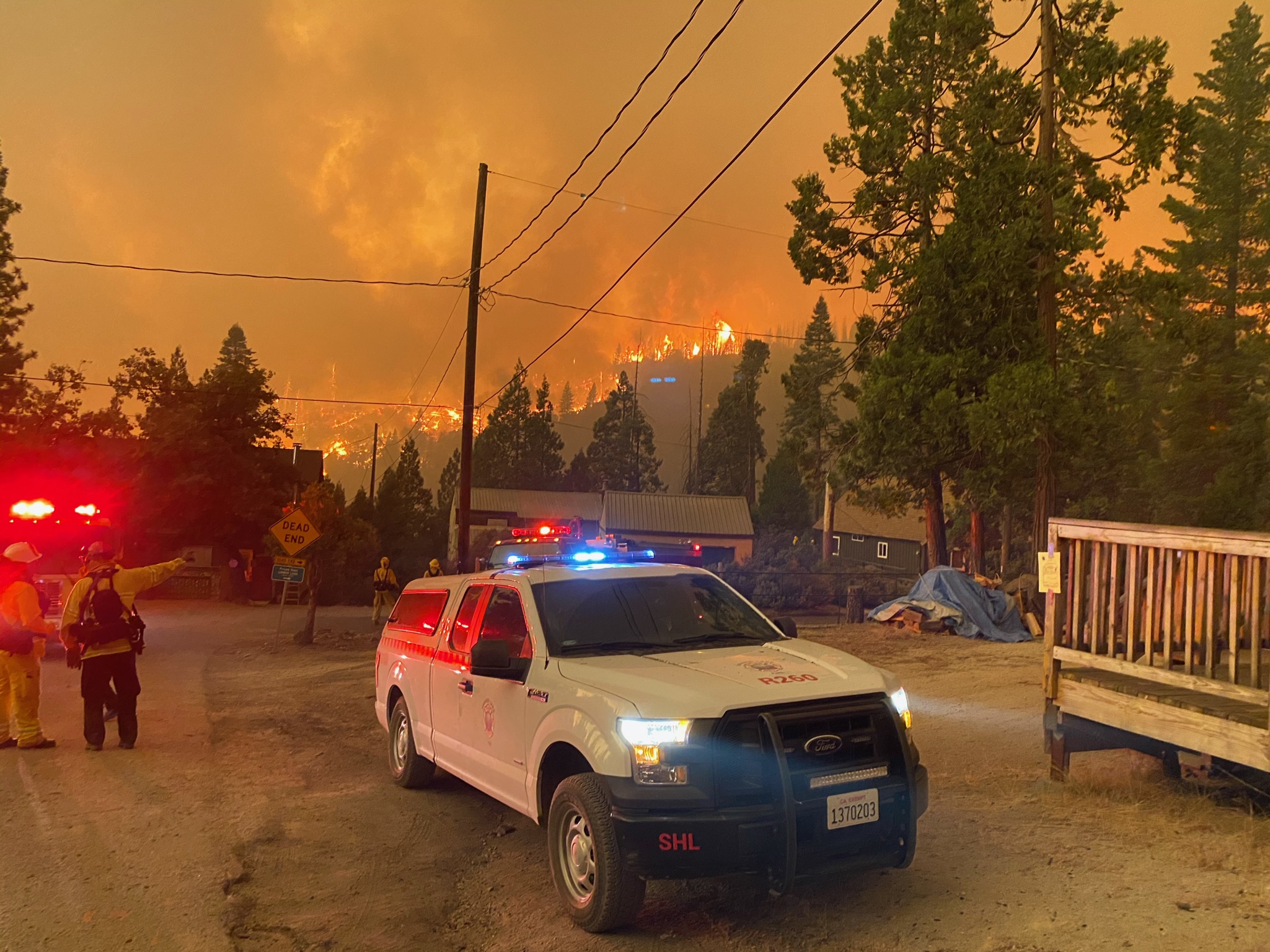 emergency crews vehicles with fire in the forest in the background