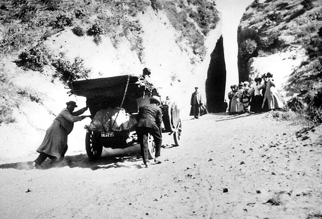 antique photo of people pushing a car up a steep hill